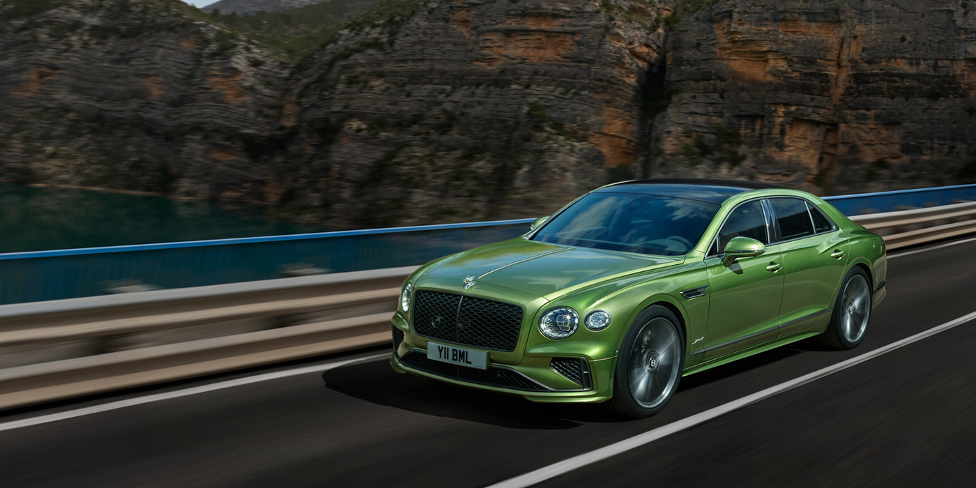 Thomas Exclusive Cars GmbH Bentley New Flying Spur Speed v8 hybrid sedan driving dynamically on a mountain road in Tourmaline Green paint