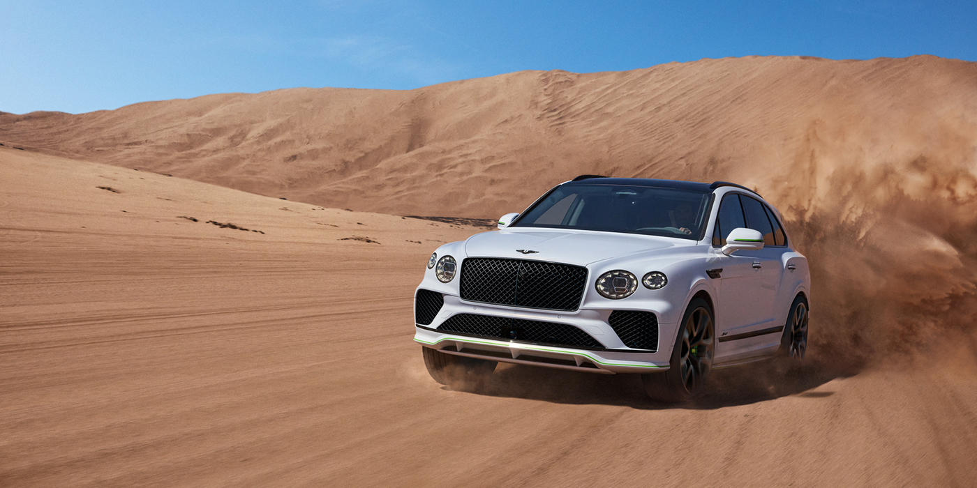 Thomas Exclusive Cars GmbH Bentley Bentayga Speed SUV front three quarter in Snow Quarts Pearlescent by Mulliner white paint driving dynamically through the desert