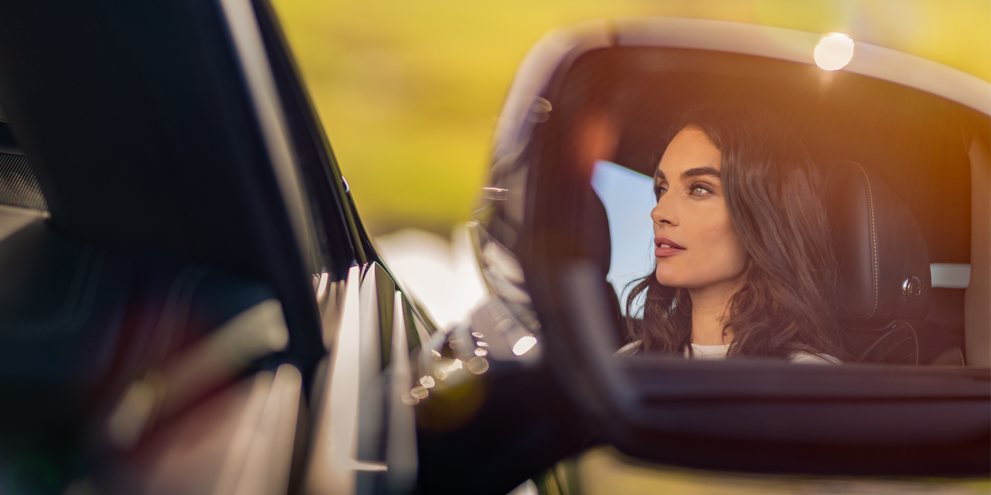 Thomas Exclusive Cars GmbH profile of dark haired woman's face in mirror of Bentley car in sunlight