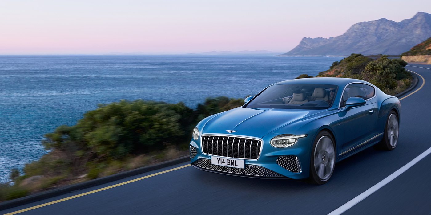 Thomas Exclusive Cars GmbH New Bentley Continental GT Azure coupe in Light Windsor blue paint with 22 inch Azure wheels and chrome grill, driving dynamically by the sea