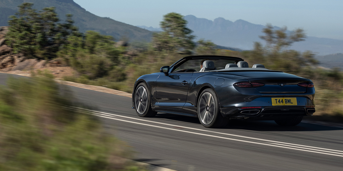 Thomas Exclusive Cars GmbH Bentley Continental GTC S convertible in Thunder blue paint rear 3/4 driving on mountain road