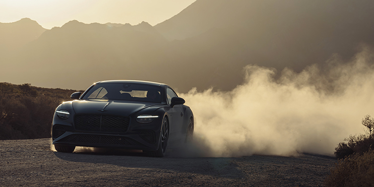 Thomas Exclusive Cars GmbH Bentley Continental GT coupe in Thunder paint front 3/4 driving with dust trail at sunset